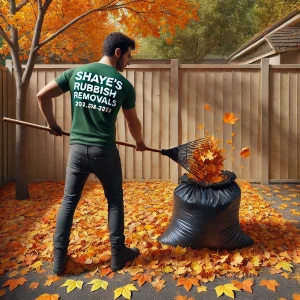 A man putting leaves that have fallen from a tree into a rubbish bag.