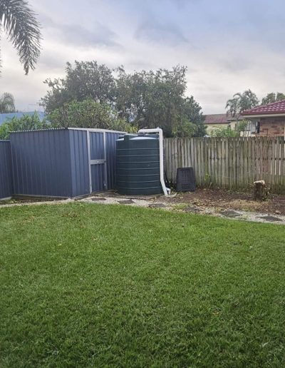 Clean yard with no more hedges or shrubs next to fence after removal of these.